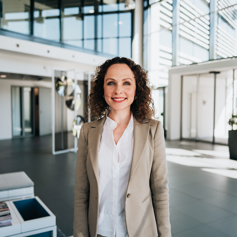 BMW employee Vanessa smiling in the entrance area of an office