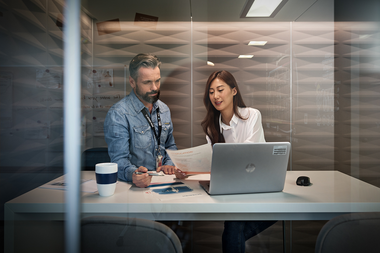 A female apprentice is having a conversation with her supervisor in a glass meeting room.