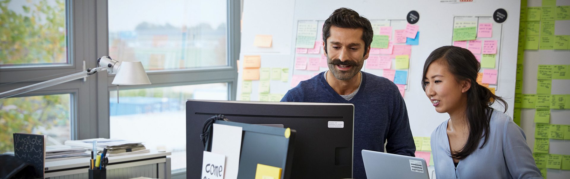 A man explaining things to a woman looking at their computer screen
