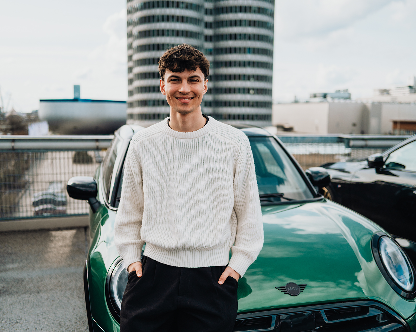 Anton, a work-study student, is leaning against a green MINI in front of the BMW four-cylinder