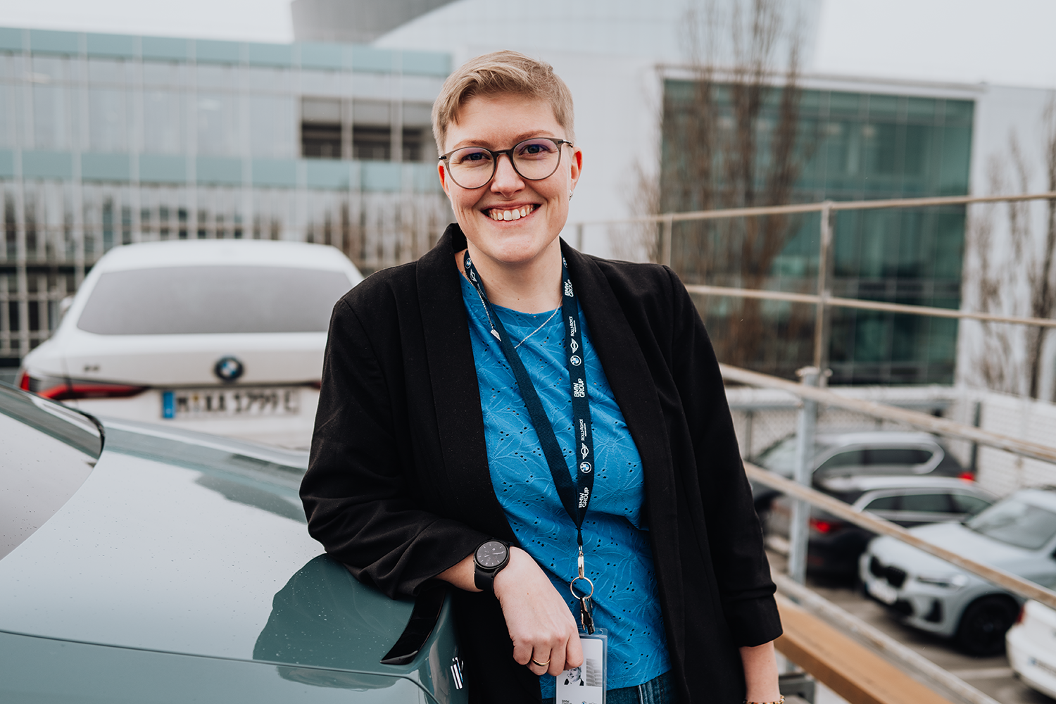 Erla leans against the trunk of a BMW i5.