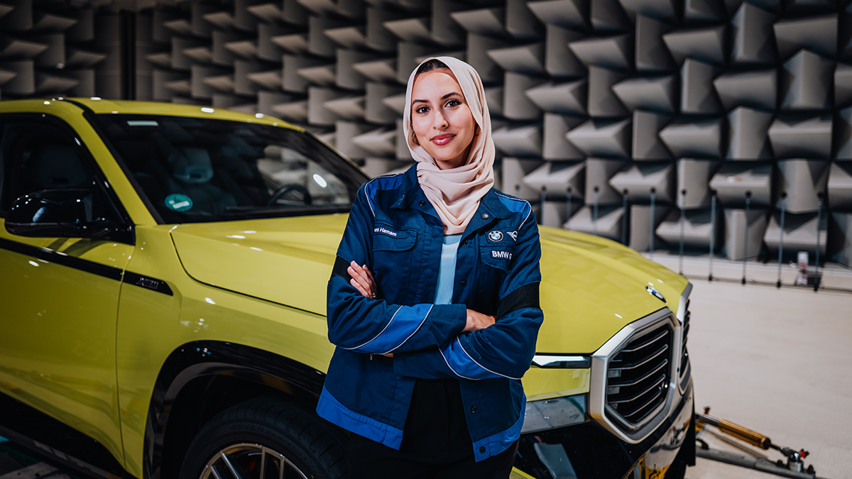 Ines in front of a BMW XM with crossed arms.