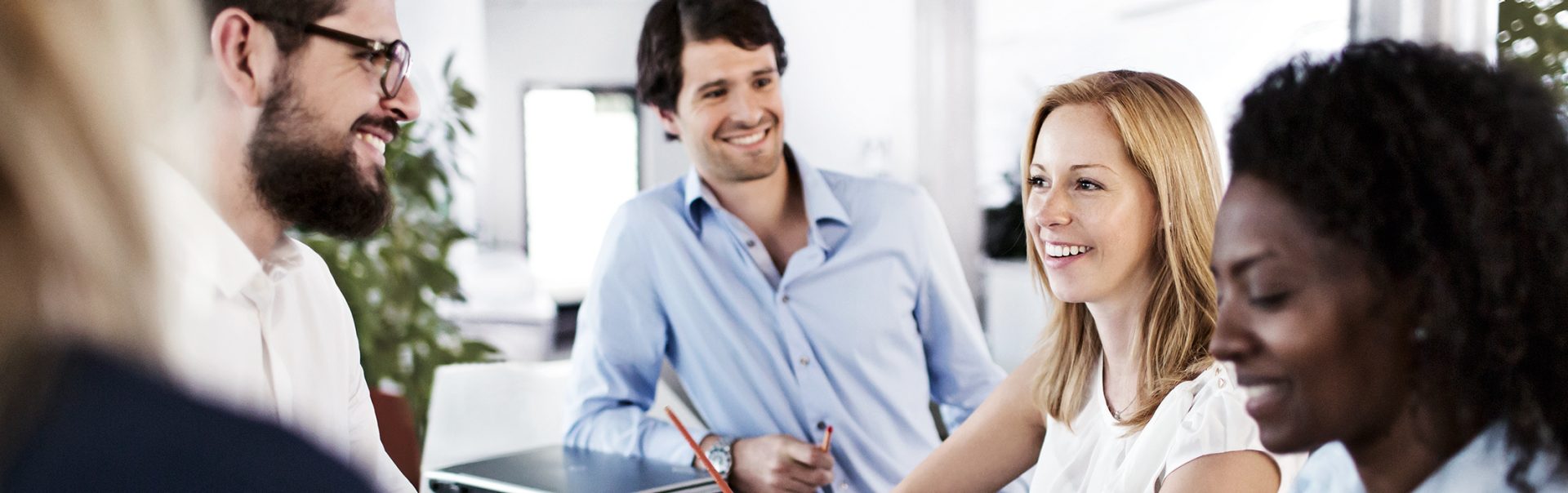 We see five young BMW employees having an animated conversation in a modern office.