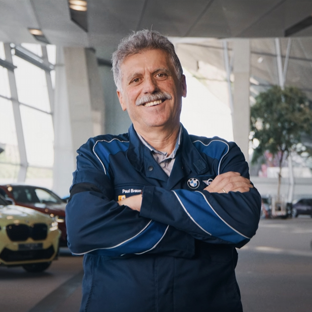 Ingenieur Paul in der BMW Welt München, lächelnd und mit verschränkten Armen