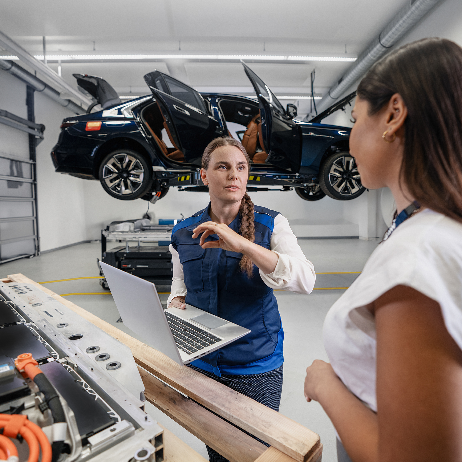 Beratungsgespräch zwischen BMW- Technikerinnen bei einem Qualitätscheck an einem Fahrzeug.