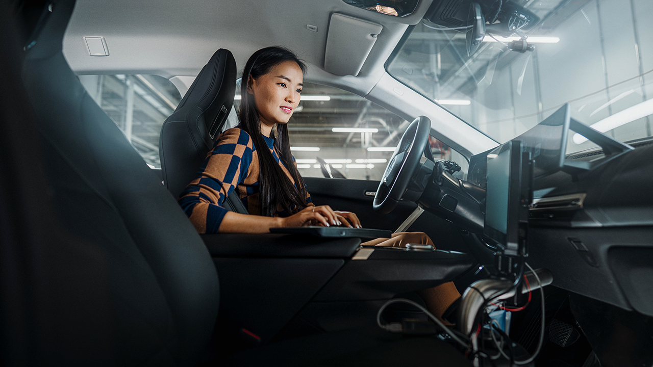 Eine Mitarbeiterin bei der BMW Group analysiert Daten mit ihrem LapTop in einem Fahrzeug.