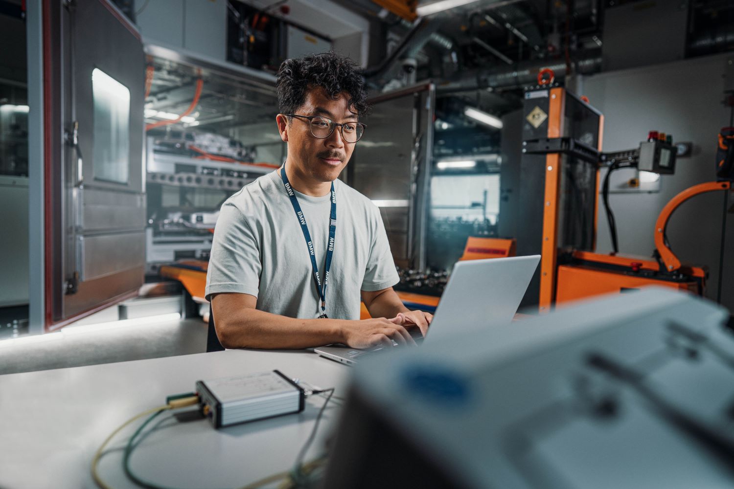 Ingenieur arbeitet konzentriert an einem Laptop in einer modernen Fabrik bei der BMW Group.