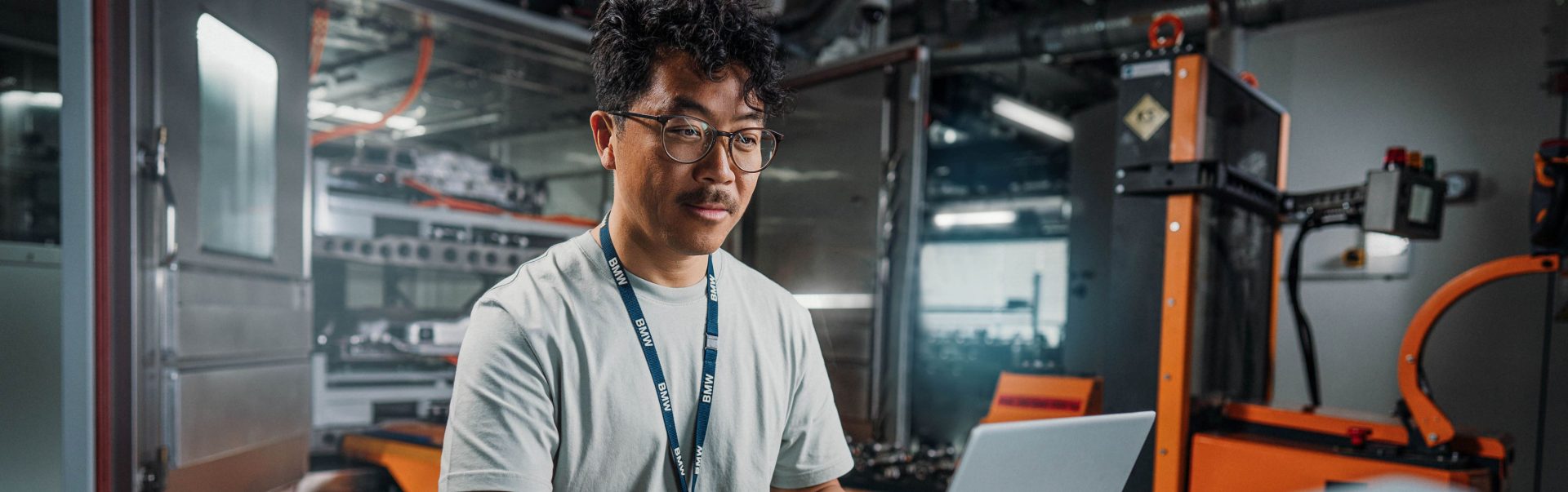 Ingenieur arbeitet konzentriert an einem Laptop in einer modernen Fabrik bei der BMW Group.
