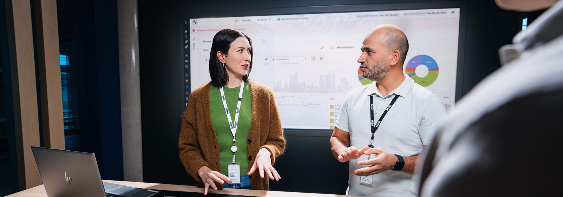 Drei Kolleg:innen bei der BMW Group unterhalten sich an einem interaktiven Tisch mit Screen