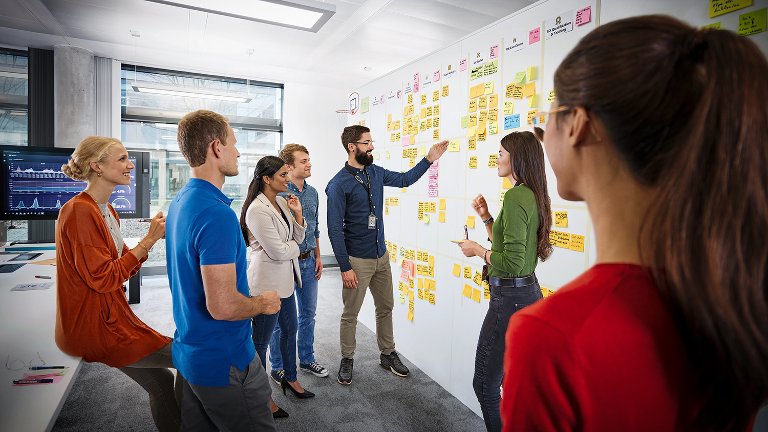 IT-Projektmanager unterhalten sich über Notizzettel, die an einer Wand kleben.