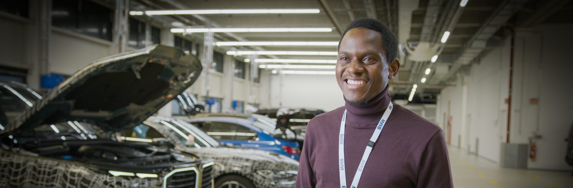 Nahaufnahme eines Software Integration Specialists neben neuen BMW Fahrzeugen.