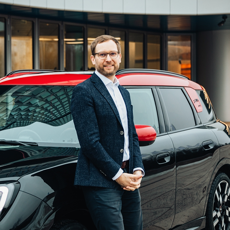 Portrait von BMW Legal Operations Officer Bernhard vor einem MINI Countryman
