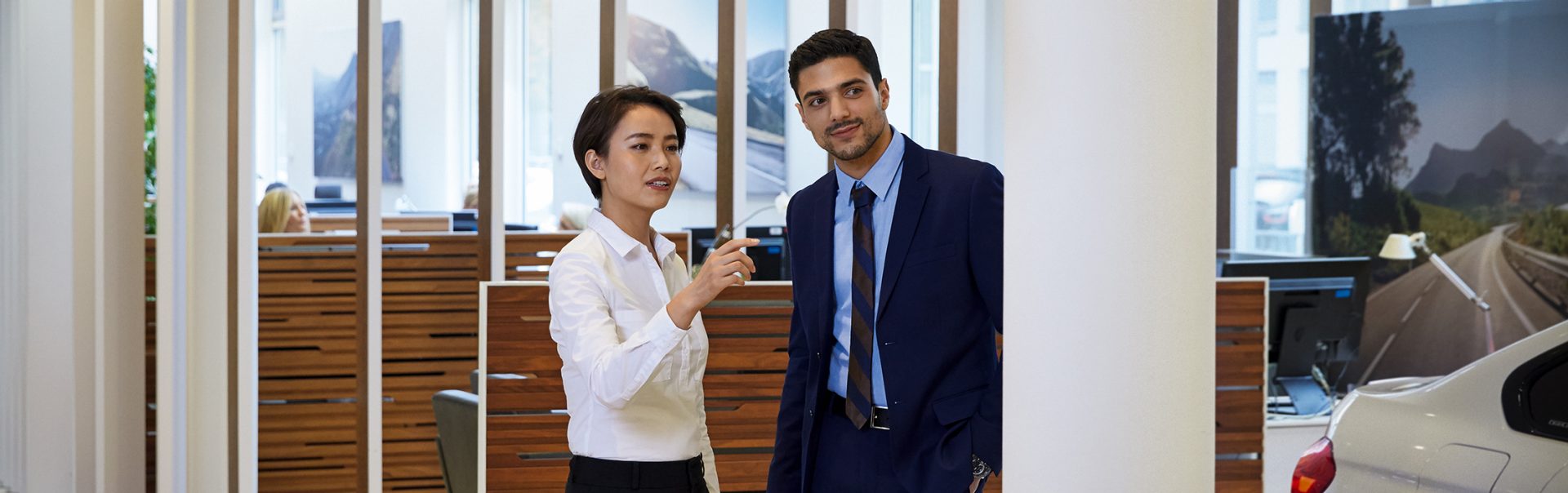 Das Bild zeigt eine junge Frau, die als Automobilverkäuferin bei BMW arbeitet, im Gespräch mit einem Kunden.