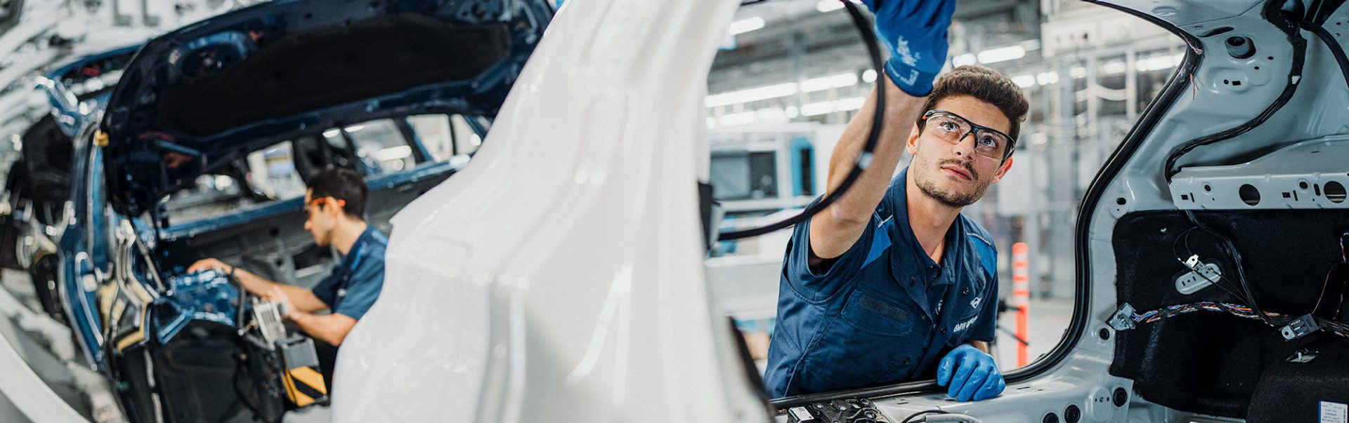 Produktionsmitarbeiter bei der Arbeit an einer Fahrzeugkarosserie.