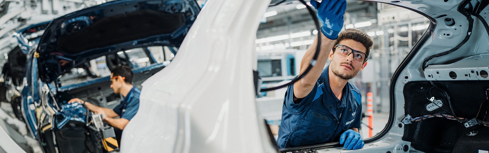 BMW Mitarbeiter in der Produktionslinie arbeitet gerade an einem neuen Fahrzeug.