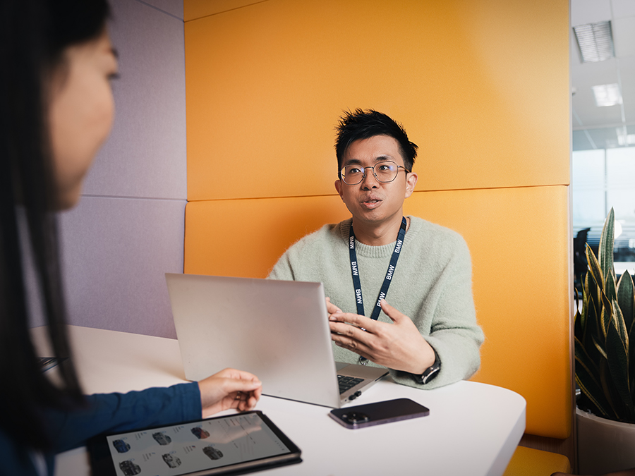 Zwei Studenten bei einer Besprechung in einer lila-orangenen Besprechungsumgebung bei der BMW Group.
