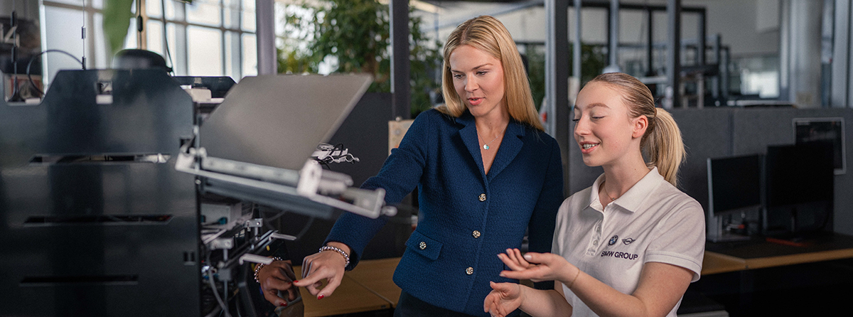 Eine Studierende mit ihrer Mentorin vor einem 3D Drucker.