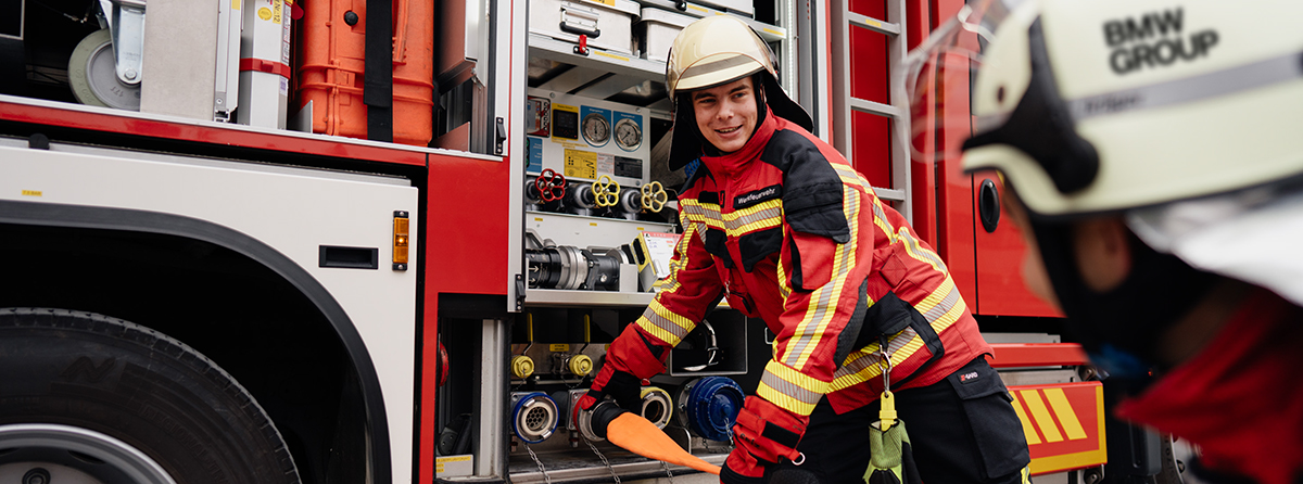 Zwei Werksfeuerwehrleute beim ausrollen eines Wasserschlauches.