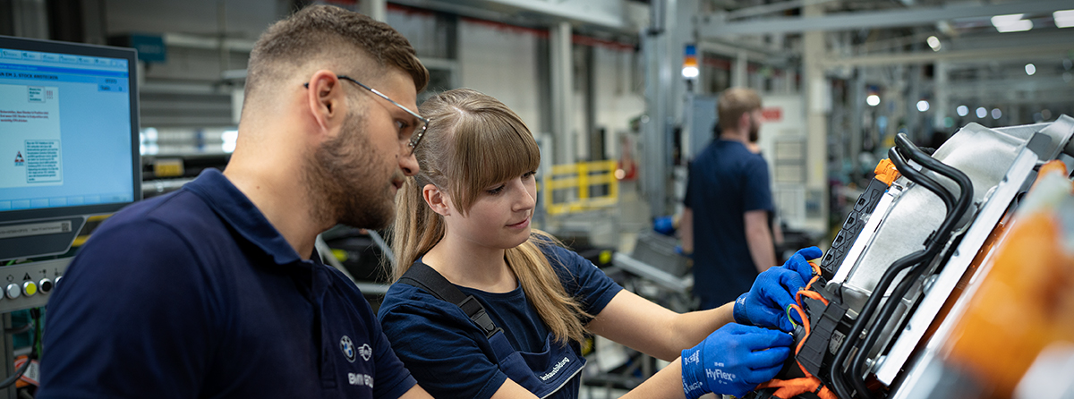 Ein Ausbilder und eine Auszubildende arbeiten an einem Gerät an der Produktions Linie.