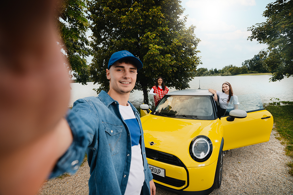 Drei Auszubildende am See mit einem gelben MINI Cooper