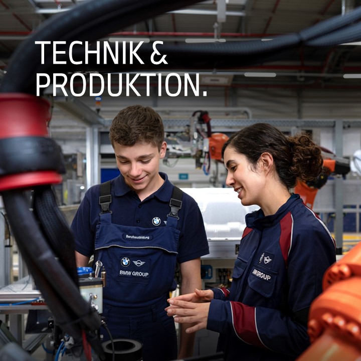 Azubi mit Ausbilderin in der Montagehalle mit Roboter