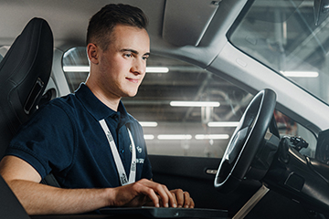 Technisches Setup im Auto mit einem auszubildendem für digitale Vernetzung bei der BMW Group, der an einem Computer arbeitet.