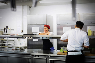Eine Systemgastronomin an der Essensausgabe in der Kantine lacht
