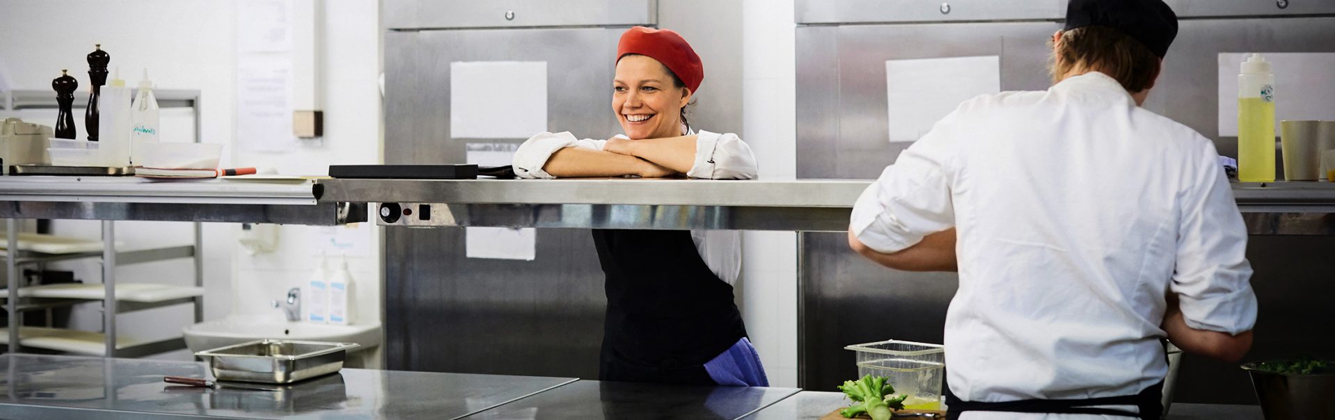 Eine Systemgastronomin an der Essensausgabe in der Kantine lacht
