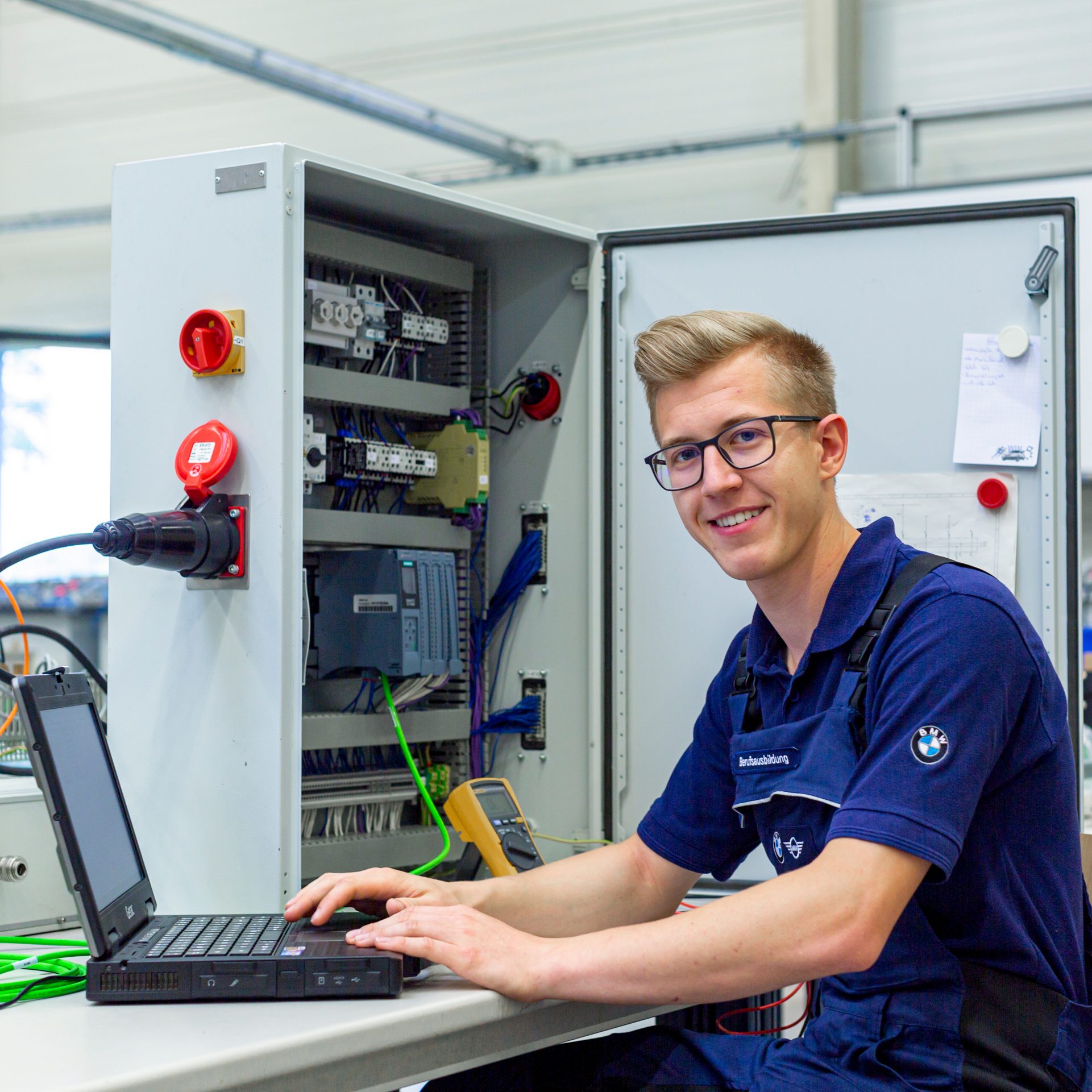 Ein Auszubildender IT-Techniker arbeitet an einem Computer in einer modernen Werkstatt bei der BMW Group.