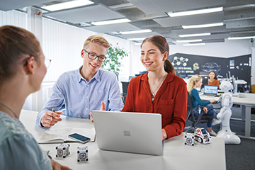 Teamarbeit zwischen drei Kaufmännern für Digitalisierungsmanagement mit Technologie in einem modernen Büro mit Robotern bei der BMW Group.