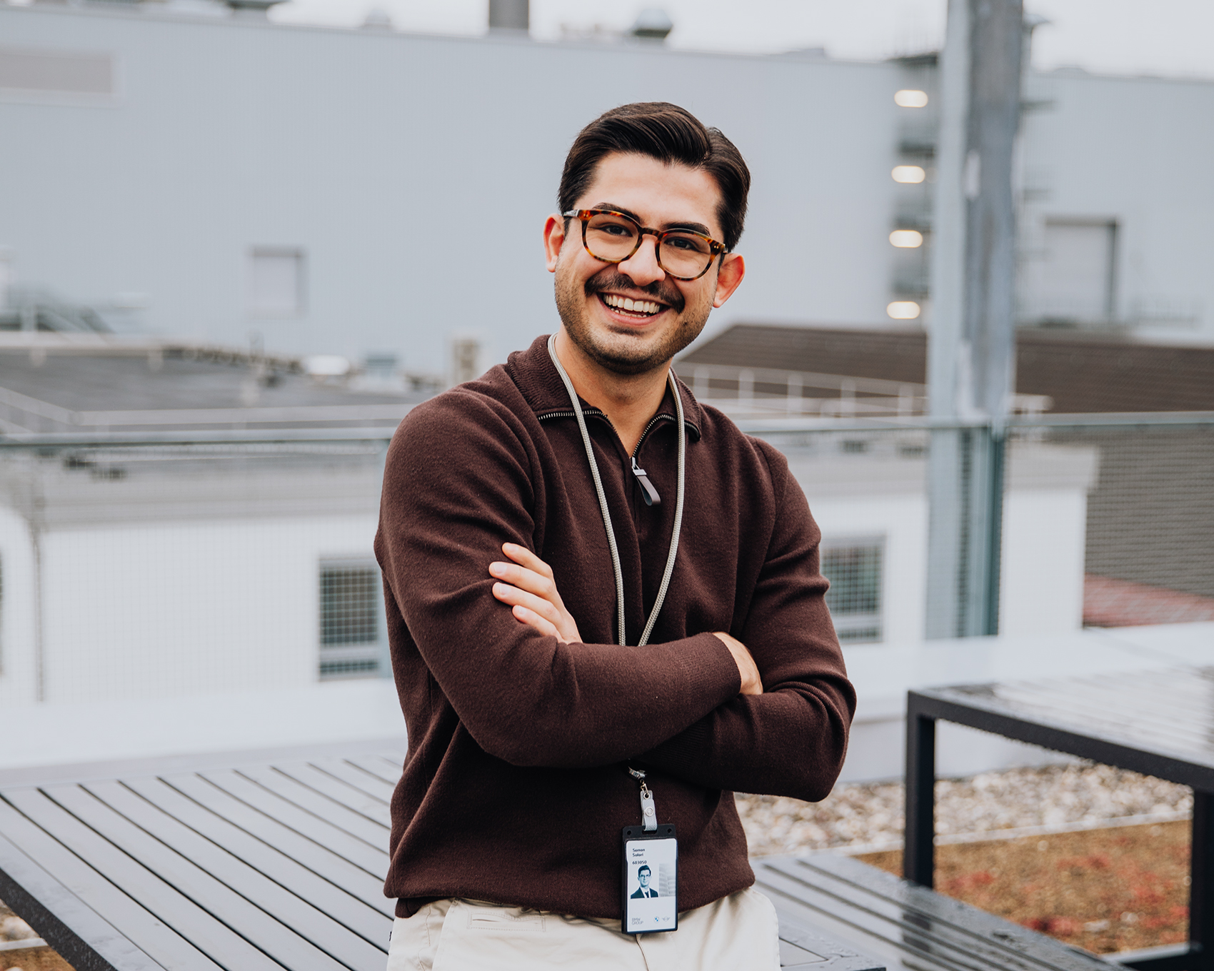 BMW IT-Spezialist Saman auf einem Rooftop mit BMW Werk im Hintergrund