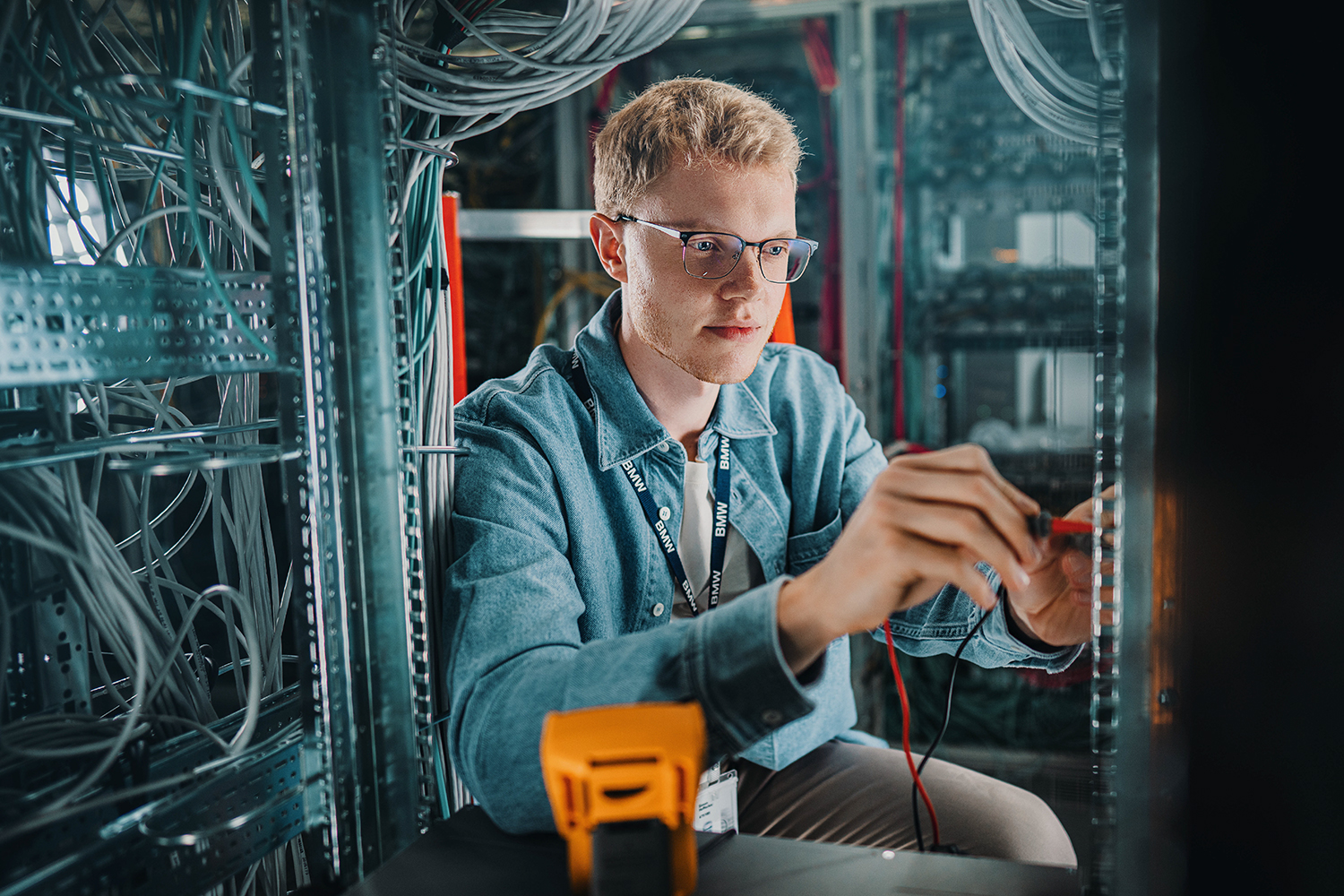 Ein junger Auszubildender als IT-Systemelektroniker bei der BMW Group führt Wartungsarbeiten an Servern durch.