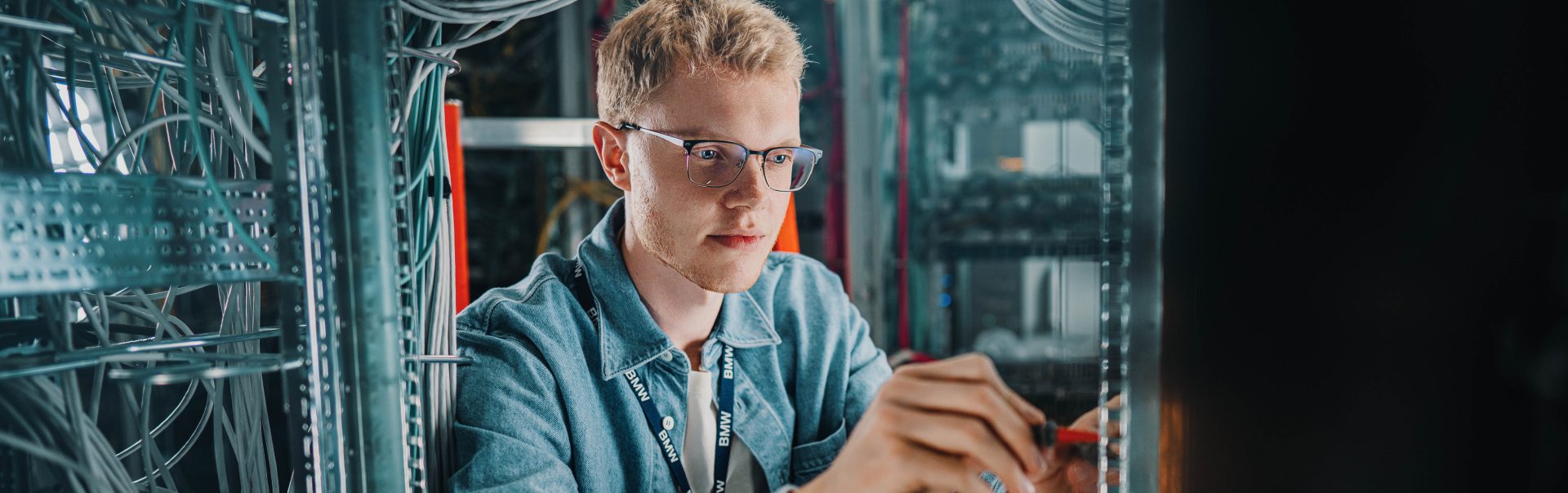 Ein junger Auszubildender als IT-Systemelektroniker bei der BMW Group führt Wartungsarbeiten an Servern durch.