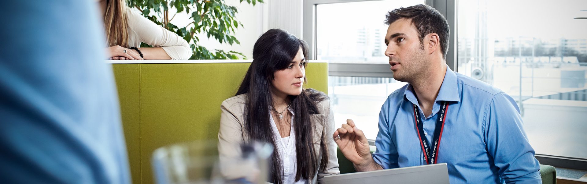 Geschäftliche Besprechung zwischen zwei Auszubildenden als Kaufleute bei der BMW Group im Einzelhandel in einem modernen Büro.