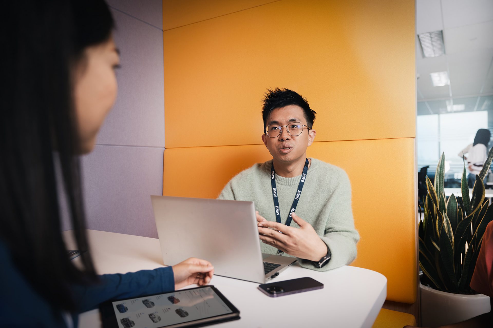 Lächelnde Auszubildende Kauffrau für Marketingkommunikation bei der BMW Group in einem modernen Büro mit Pflanzen.