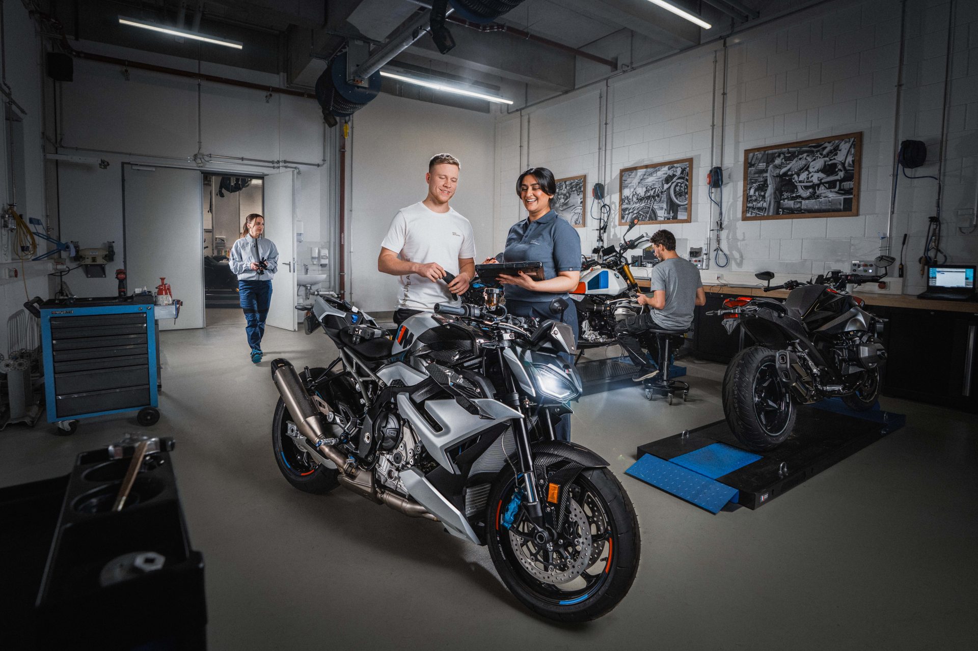 Zwei Auszubildende Motorradtechniker in einer BMW Motorradwerkstatt arbeiten an einem Motorrad.