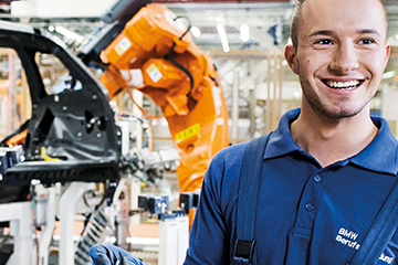 Ein Auszubildender zwischen Maschinen und Fahrzeugteilen bei der BMW Group.