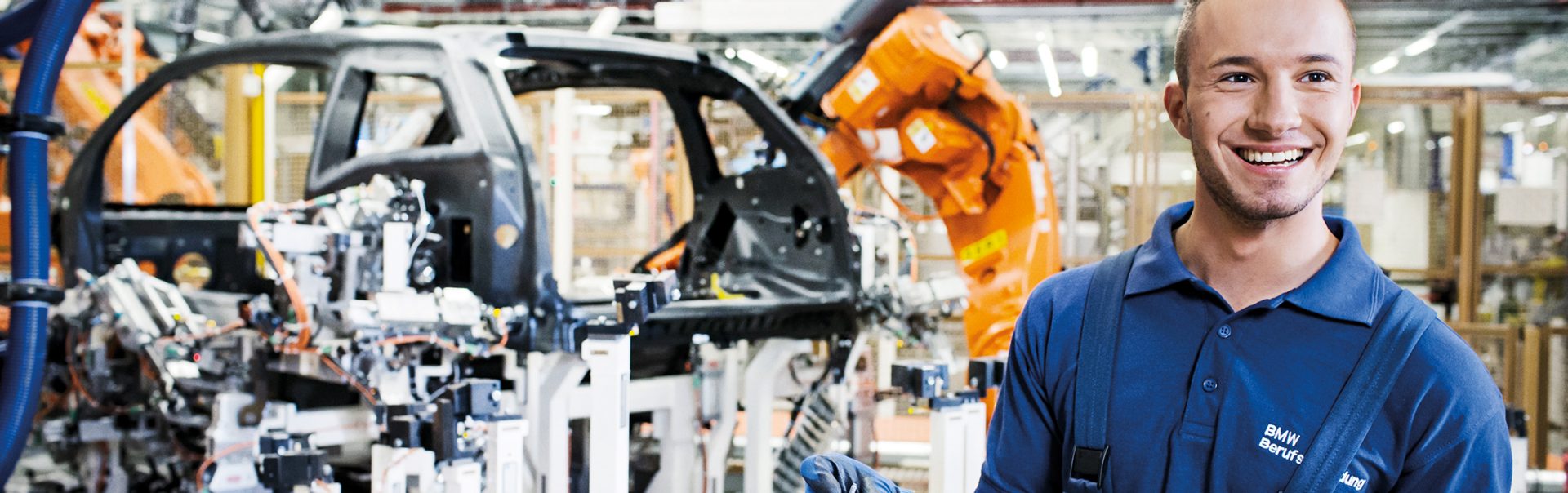 Ein Auszubildender zwischen Maschinen und Fahrzeugteilen bei der BMW Group.