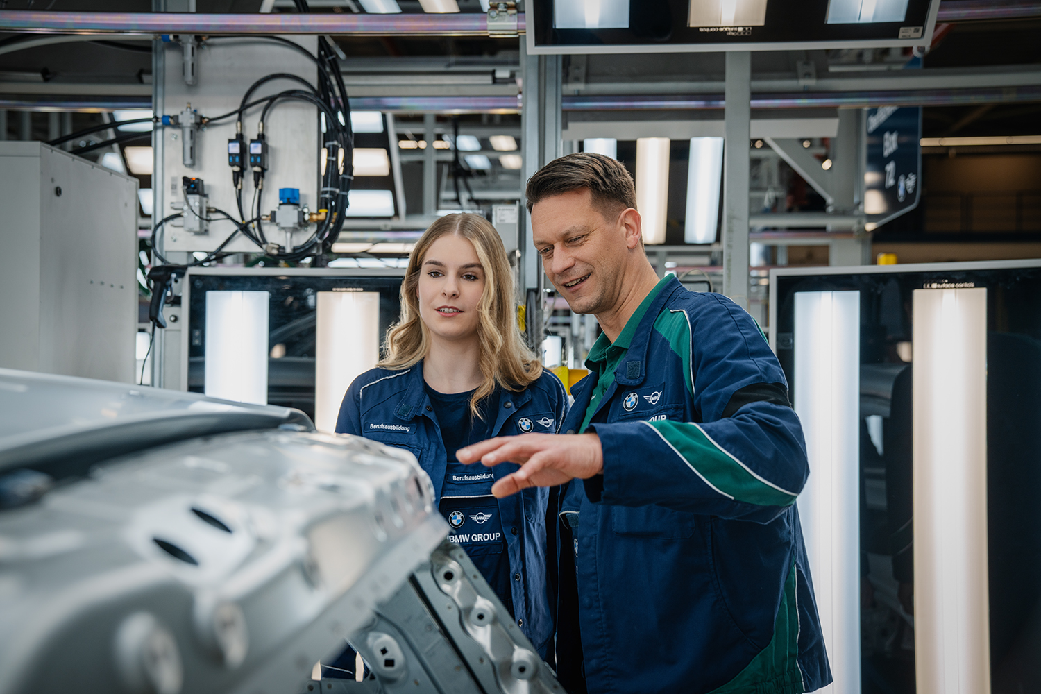 Technische Ausbildung bei der BMW Group, Mitarbeiter erklärt einer Auszubildenden den Produktionsprozess.