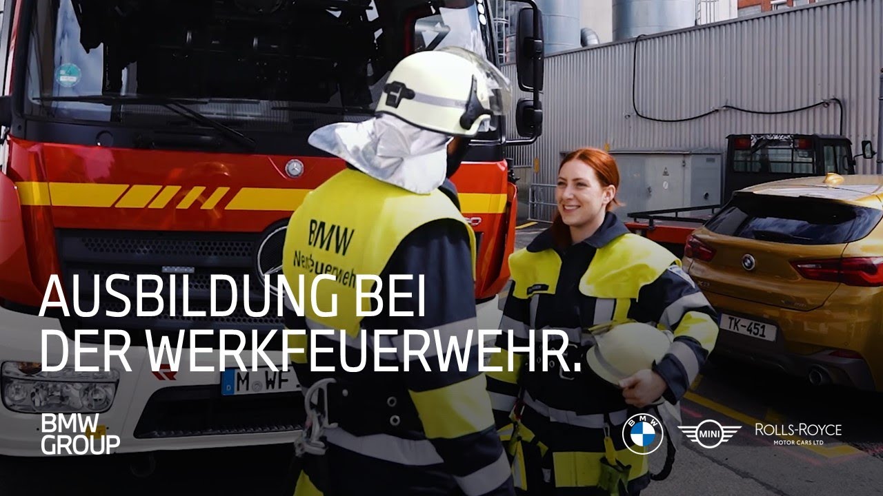 Zwei Azubis bei der BMW Werkfeuerwehr vor dem Feuerwehrauto. Einblicke in die Ausbildung bei der Werksfeuerwehr.
