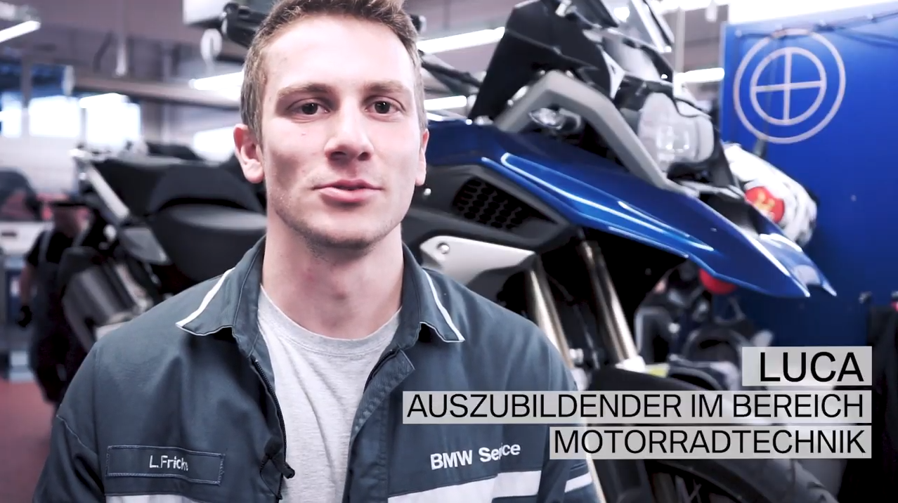 Auszubildender im Bereich Motorradtechnik bei der BMW Group, steht vor einer blauen BMW-Motorrad.