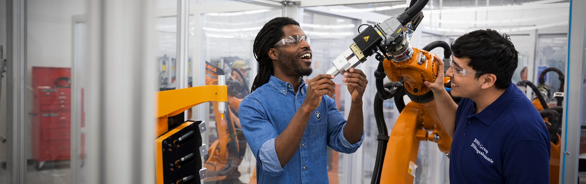 Das Bild zeigt einen Azubi und seinen Ausbilder bei der Arbeit am Roboter.