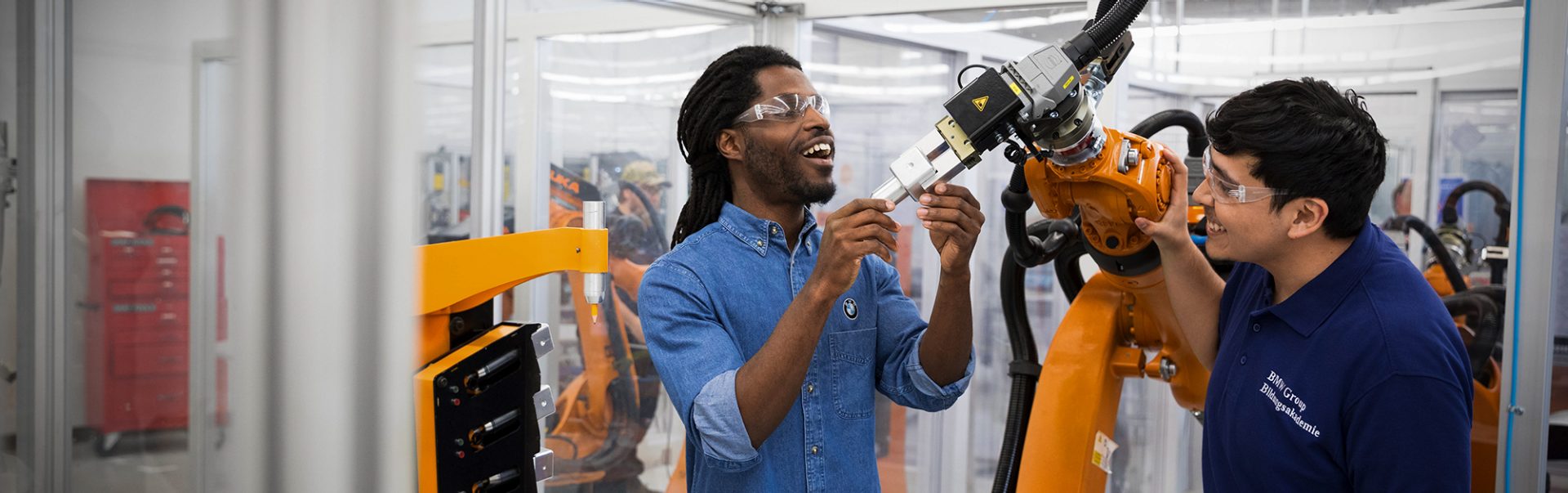 Ein Azubi und sein Ausbilder bei der Arbeit am Roboter bei der BMW Group.