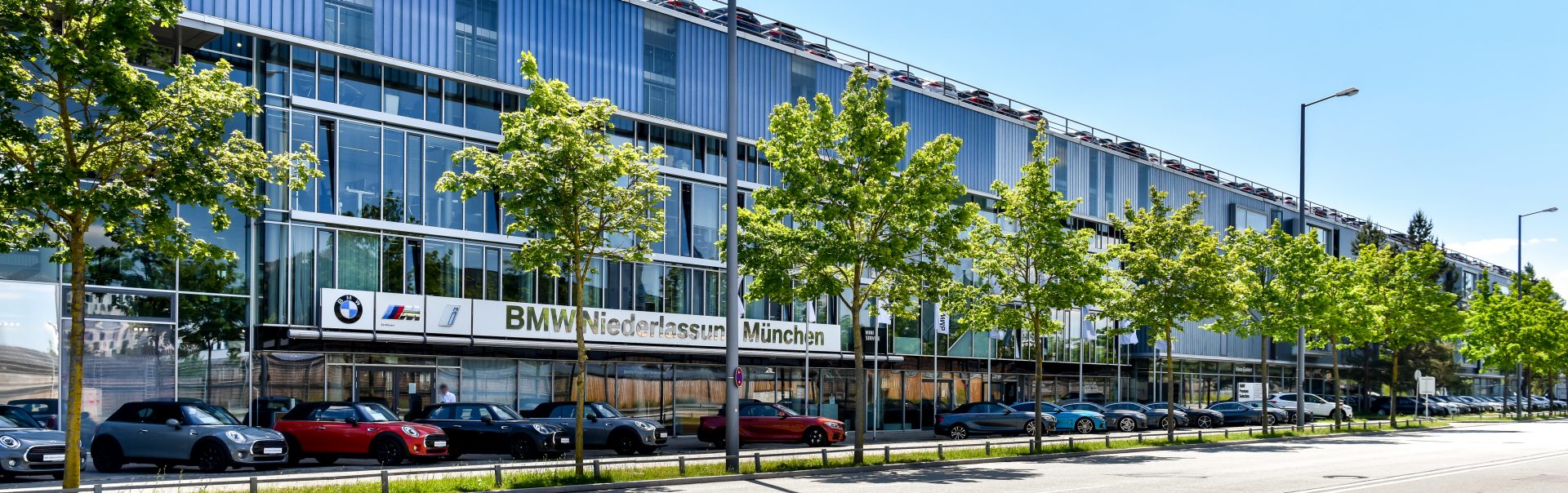 Außenansicht der BMW Niederlassung in München mit verschiedenen BMW und MINI Modellen.
