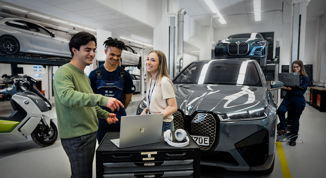 Das Bild zeigt drei Auszubildende in einer BMW Werkstatt.
