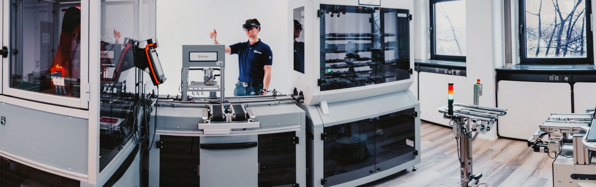 Innenansicht eines Labors der BMW Group mit vielen verschiedenen Geräten und einem Azubi der mit einer VR-Brille experimentiert.