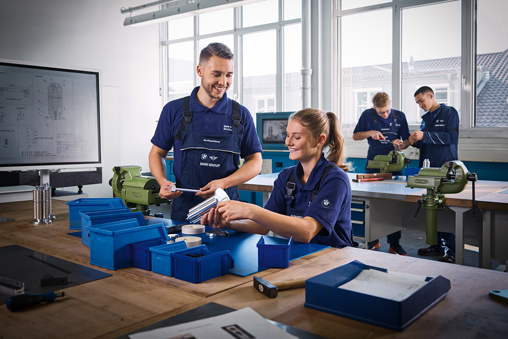 Azubis arbeiten an einem Schraubstock in der Werkstatt