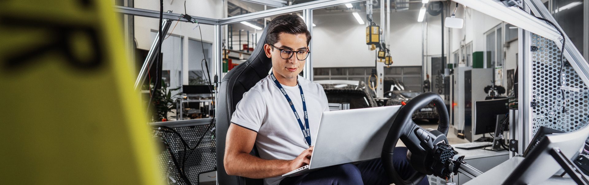 Mitarbeiter für Cyber Security bei der BMW Group arbeitet am Fahrsimulator in der Werkstatt.