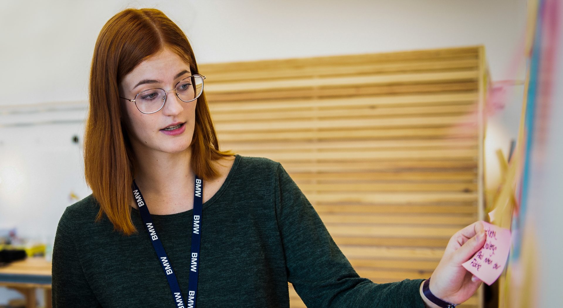 Eine Duale Studentin für Künstliche Intelligenz klebt einen Notizzettel an eine Wand.