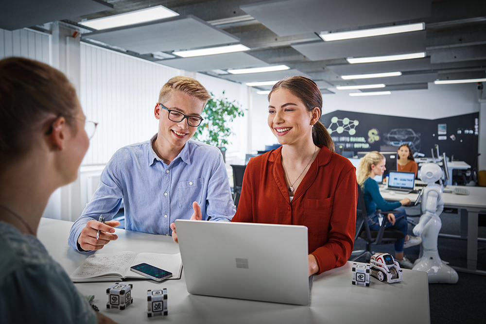 Zwei lächelnde Kollegen in einem Büro der BMW Group, die an einem Projekt arbeiten.